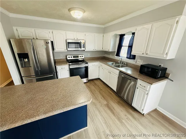 a kitchen with stainless steel appliances a refrigerator sink stove microwave and cabinets