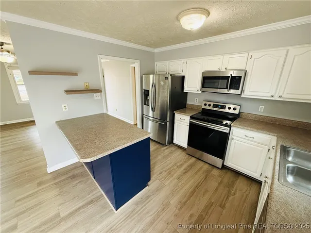 a kitchen with stainless steel appliances a stove top oven a sink dishwasher a refrigerator and cabinets with wooden floor