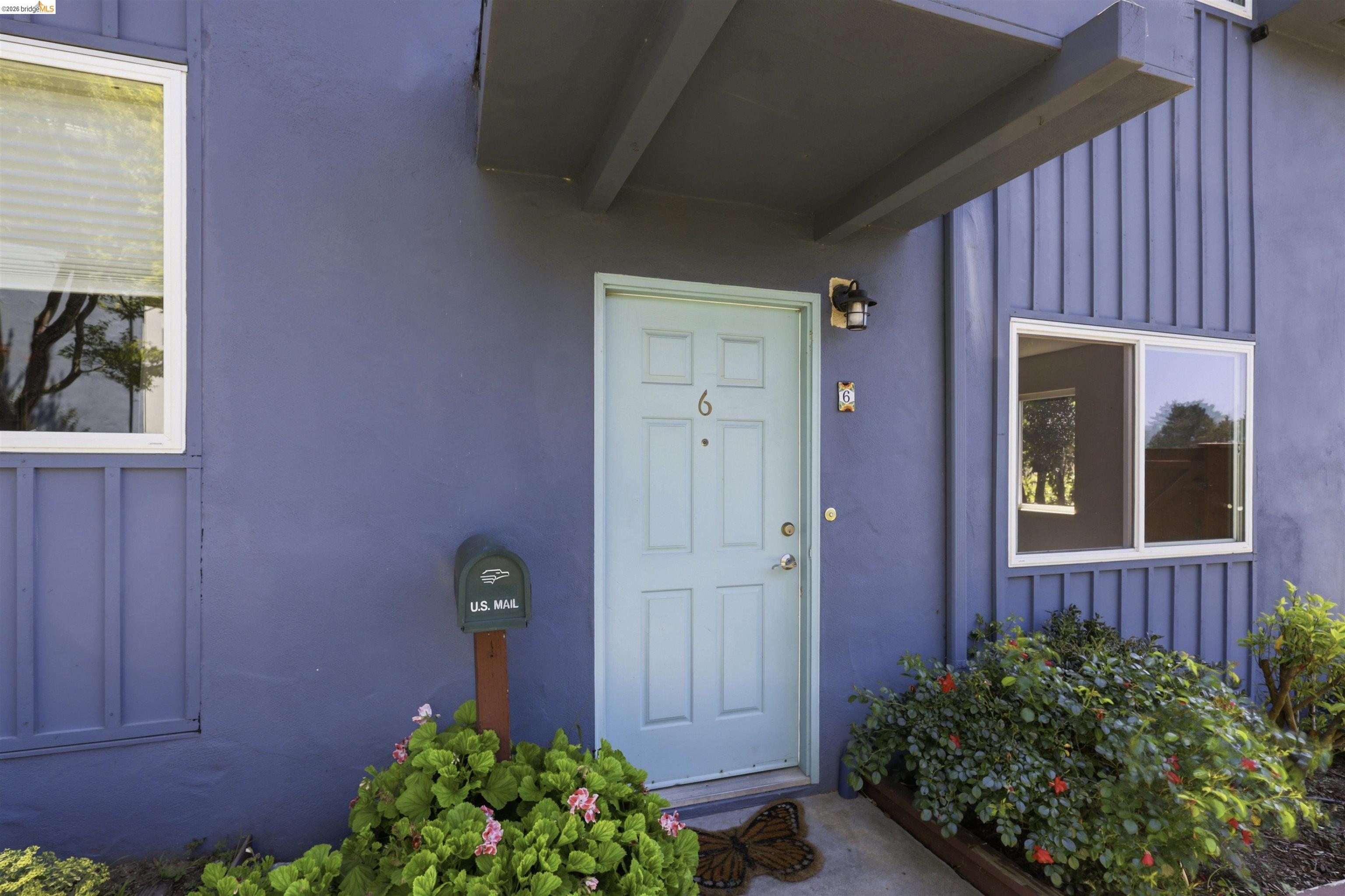 Exterior featuring a light blue entry door, an overhead awning, and dark blue siding with vertical accents