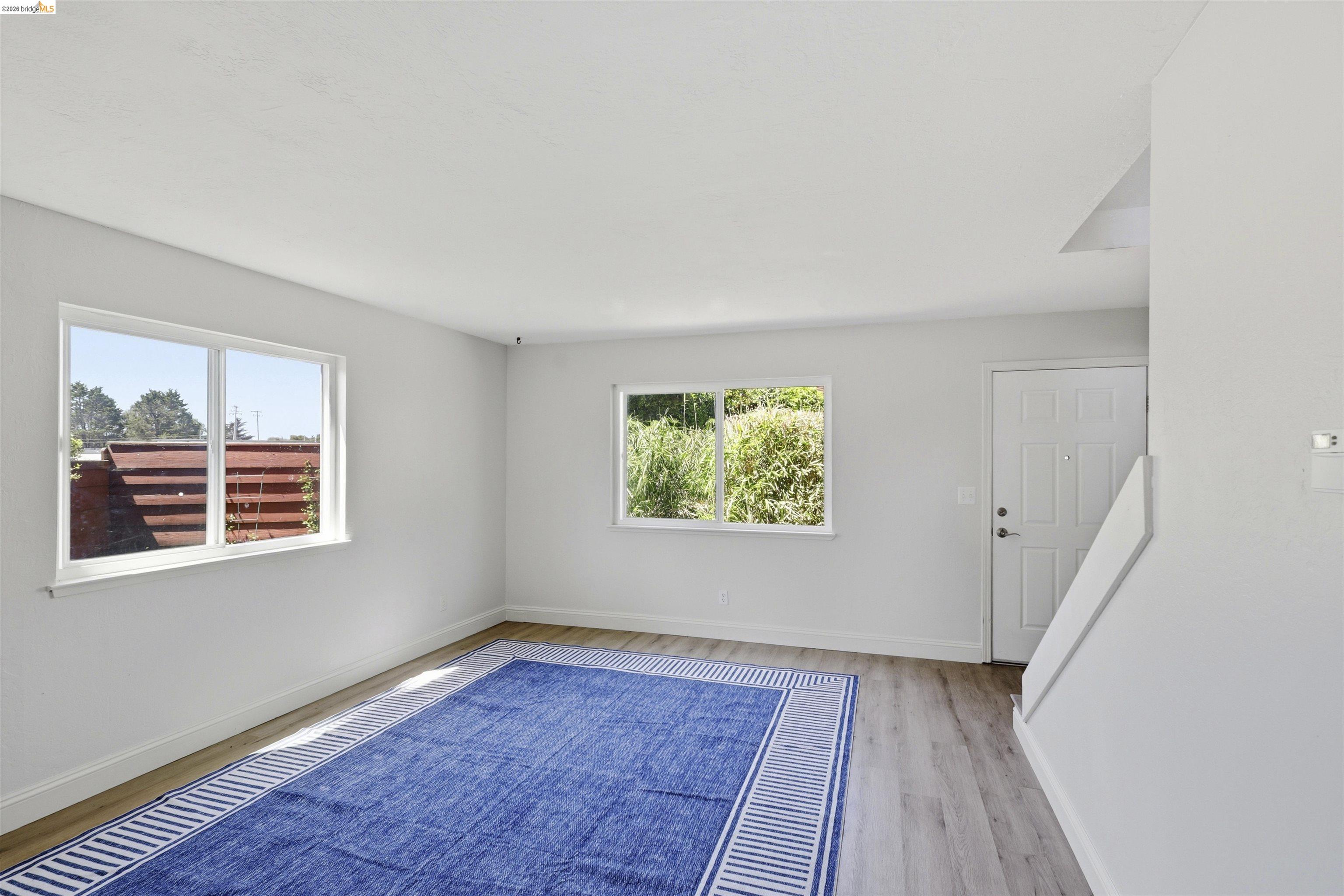 7555 Sunset Way, Unit 6 Aptos, CA 95003 - Photo 13 of 37 Open-concept living area featuring light wood-finish flooring, white walls, and two large windows providing natural illumination