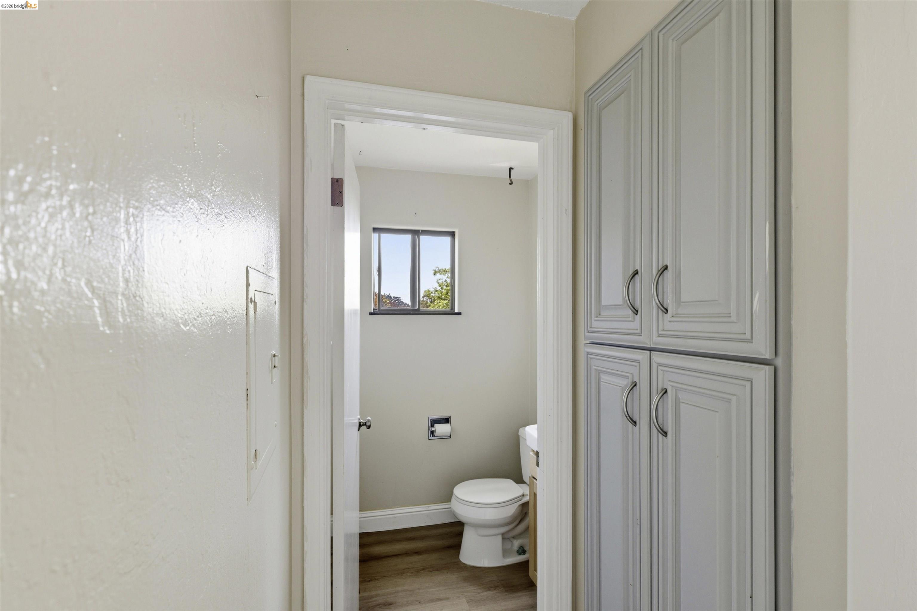 7555 Sunset Way, Unit 6 Aptos, CA 95003 - Photo 20 of 37 Bathroom featuring light gray shaker-style cabinetry with curved handles, wood-finish flooring, a window, and a white toilet