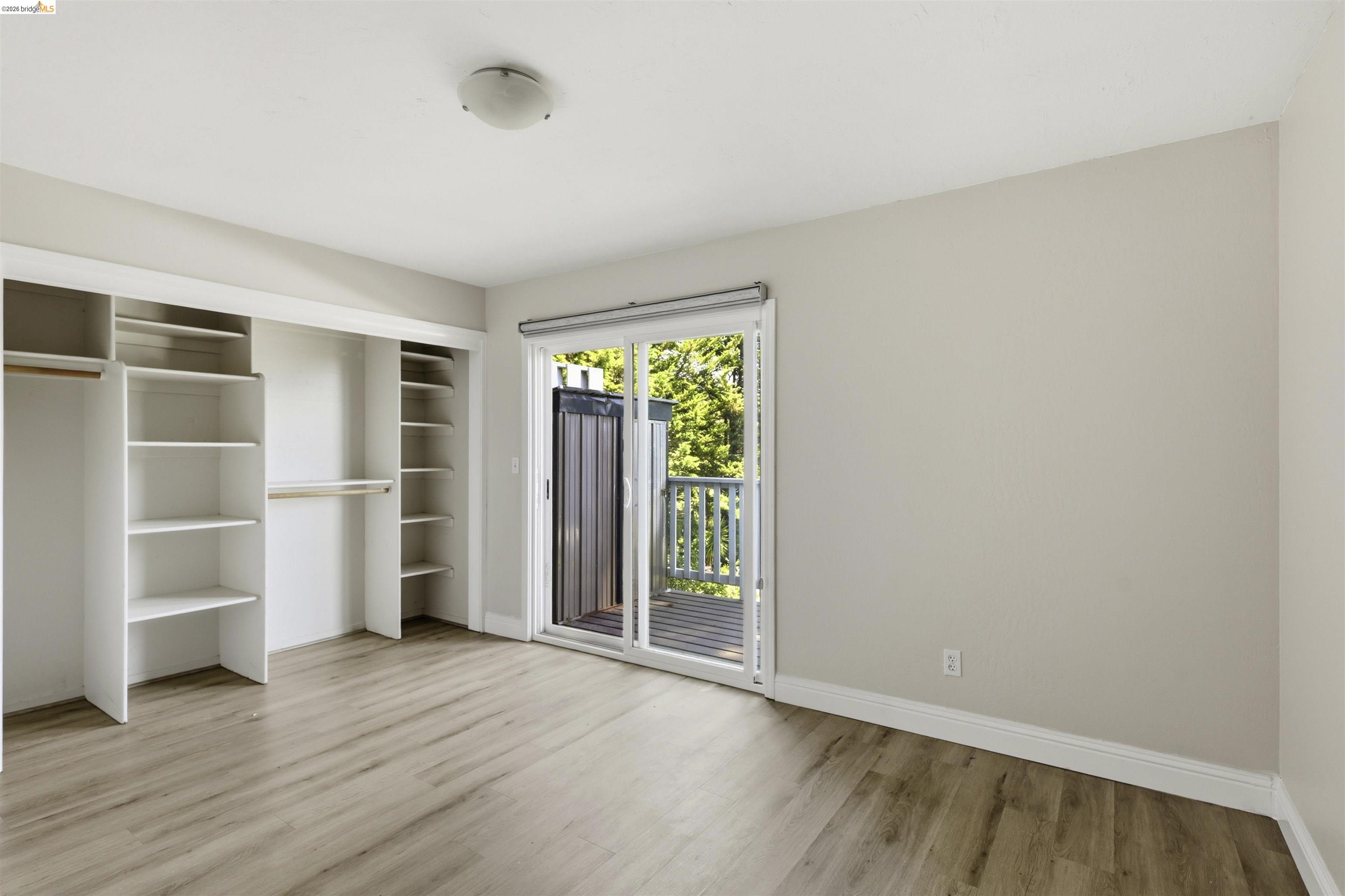 7555 Sunset Way, Unit 6 Aptos, CA 95003 - Photo 26 of 37 Room featuring wood-finish flooring, a sliding glass door leading to a balcony, and built-in closet shelving