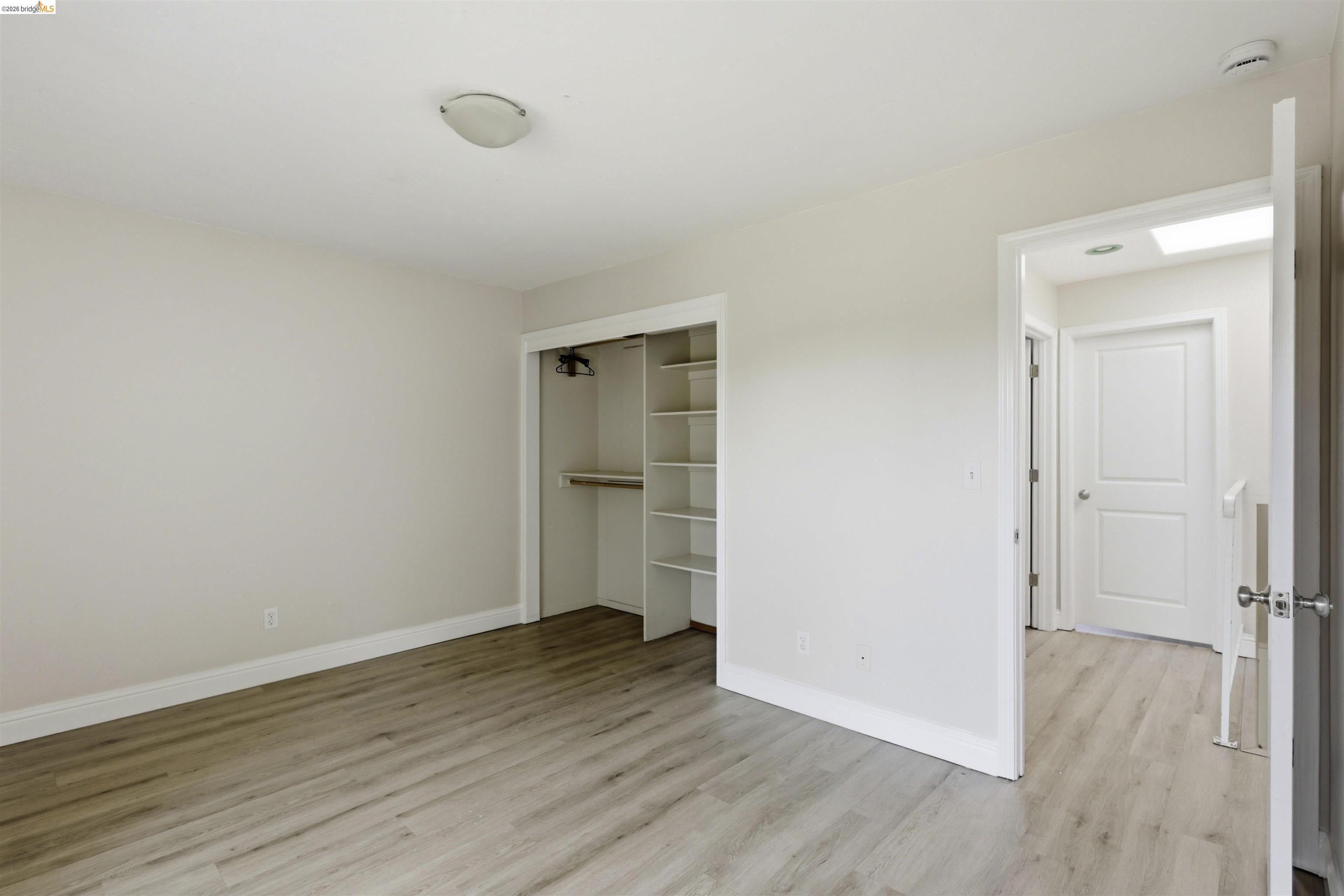 7555 Sunset Way, Unit 6 Aptos, CA 95003 - Photo 28 of 37 Room featuring wood-finish flooring, a built-in closet with shelving and hanging rod, light neutral wall paint, and white trim