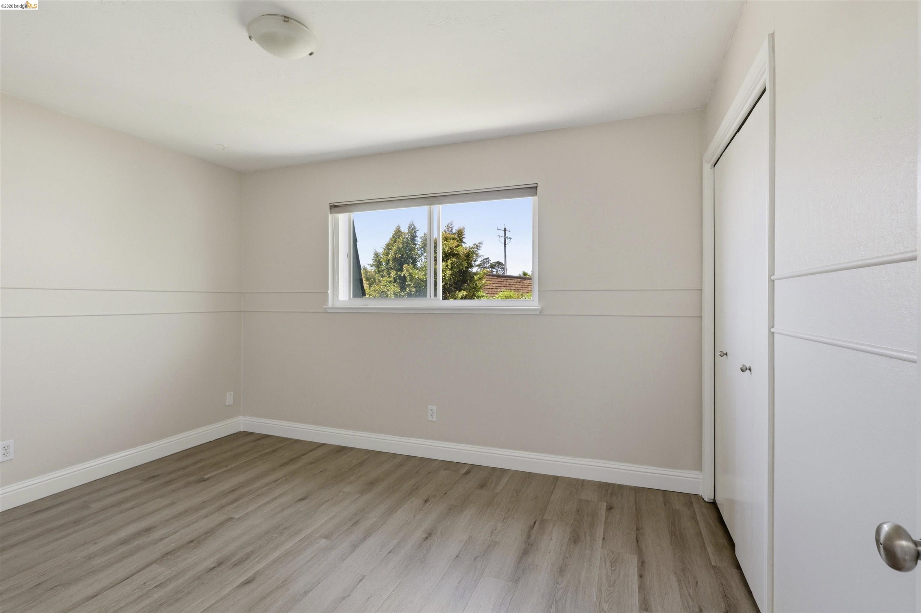 7555 Sunset Way, Unit 6 Aptos, CA 95003 - Photo 32 of 37 Spacious room featuring wood-finish flooring, a double-panel window, baseboard trim, and a bi-fold closet with contemporary doors