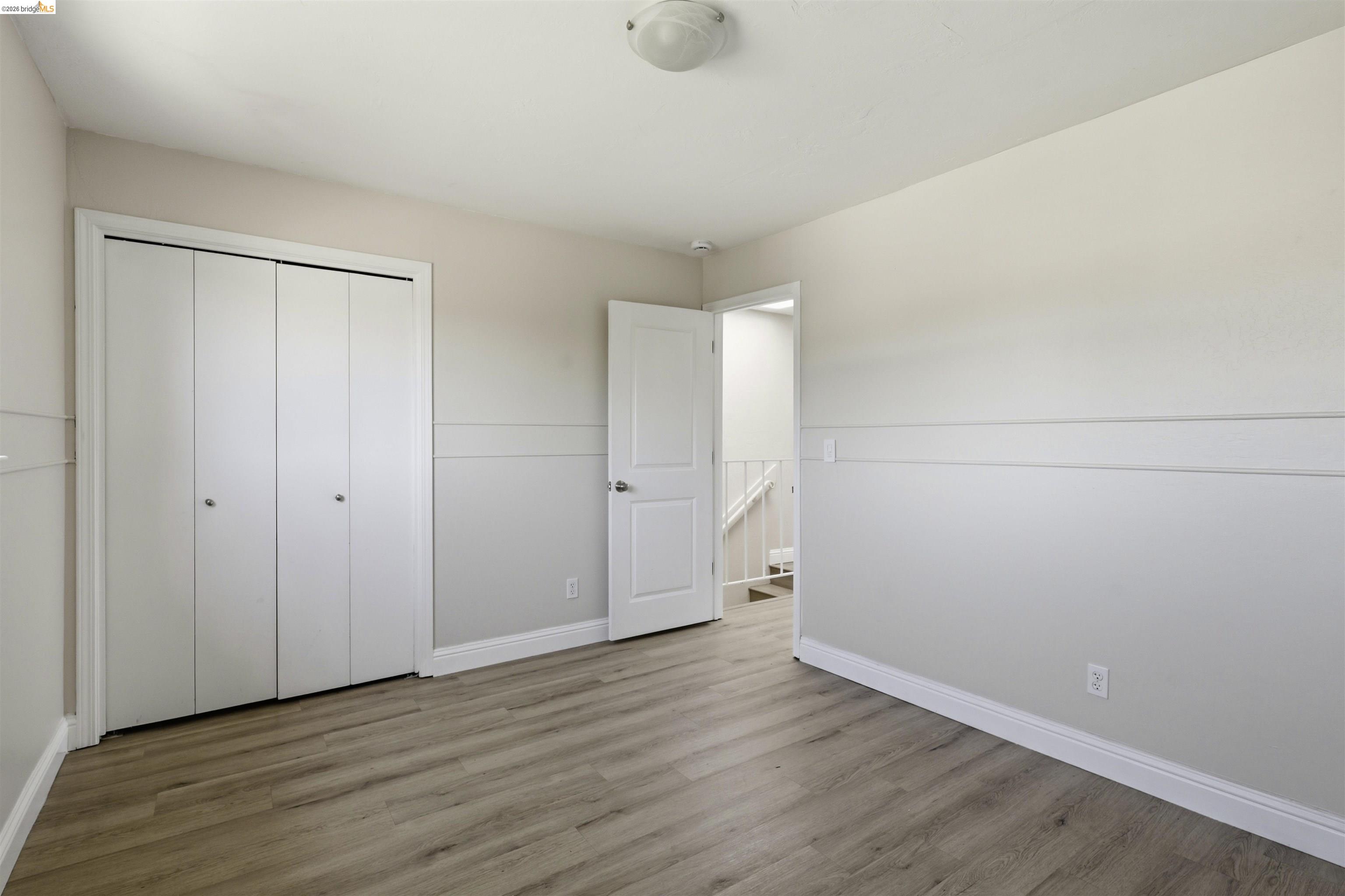 7555 Sunset Way, Unit 6 Aptos, CA 95003 - Photo 33 of 37 Room featuring wood-finish flooring, two-tone painted walls with wainscoting, and a white bi-fold closet