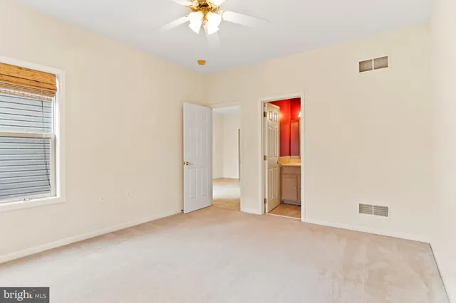 an empty room with a chandelier fan and windows