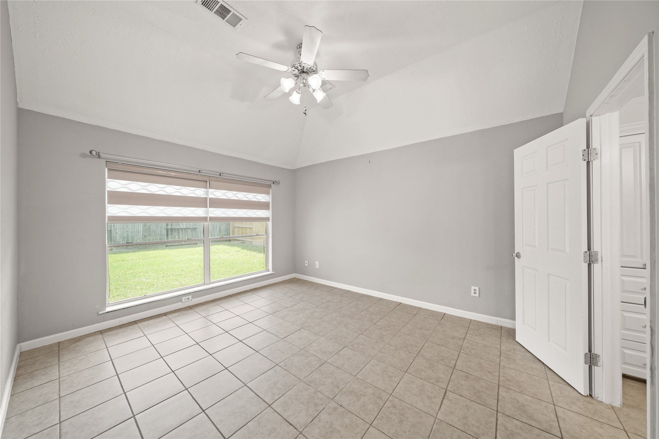 8134 Blue Jay Street Baytown, TX 77523 - Photo 18 of 31 The expansive primary suite showcases vaulted ceilings, custom trim detailing, and a refined neutral palette, offering a serene and relaxing retreat. Generous natural light and a recently installed ceiling fan enhance both comfort and ambiance.
