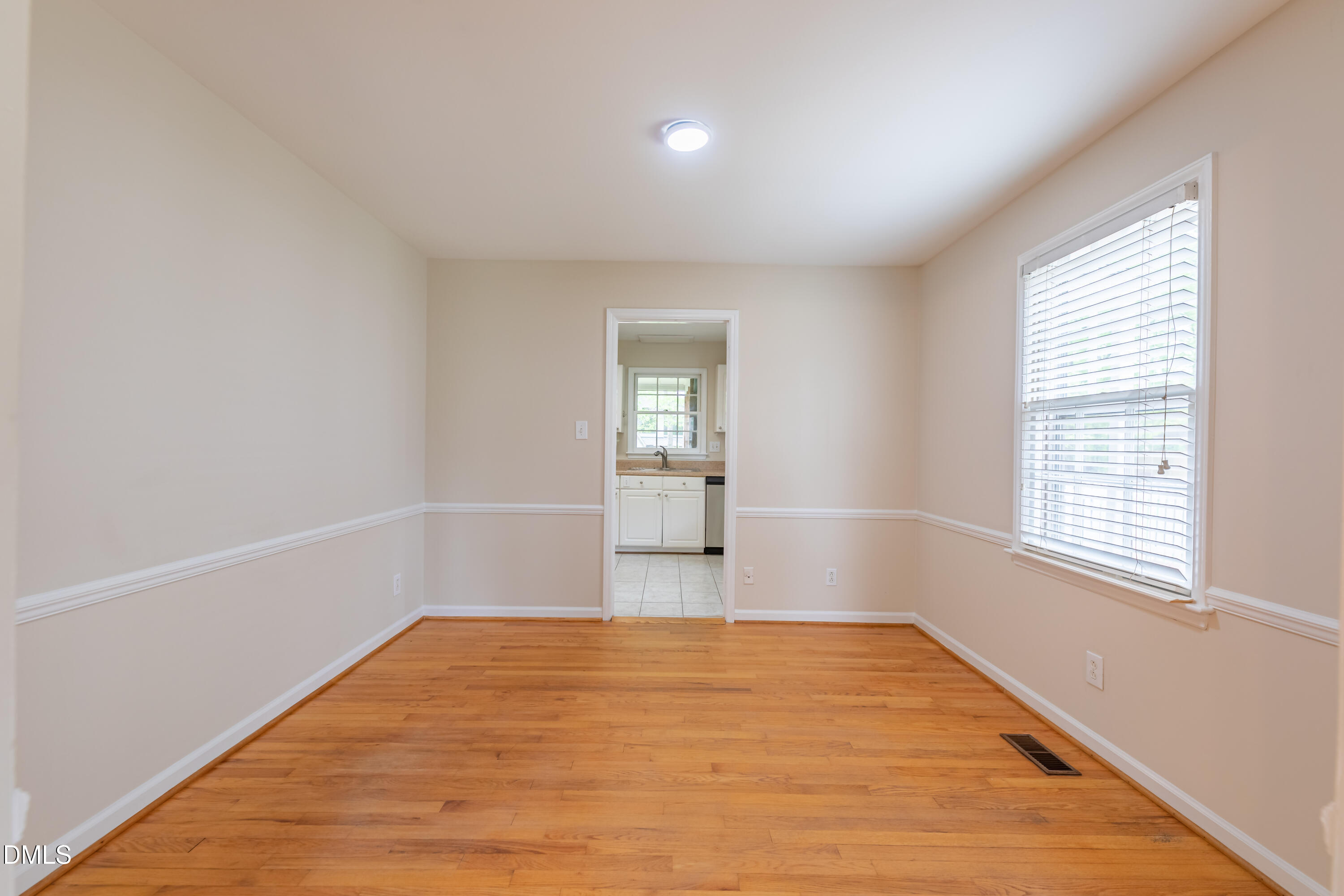 408 Ortega Road Raleigh, NC 27609 - Photo 5 of 25 an empty room with wooden floor and windows