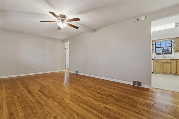 an empty room with wooden floor and ceiling fan