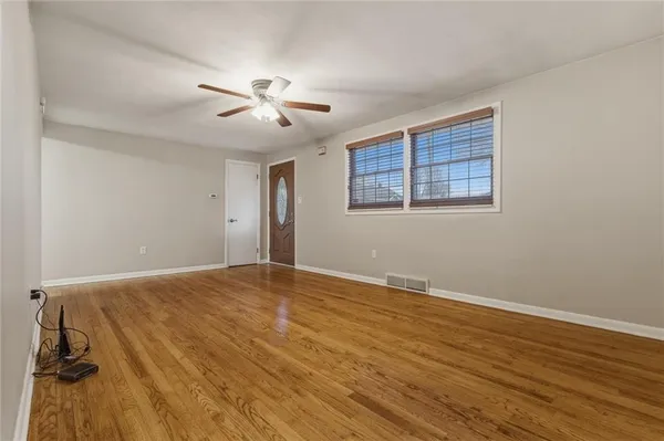 a view of an empty room with a window and wooden floor