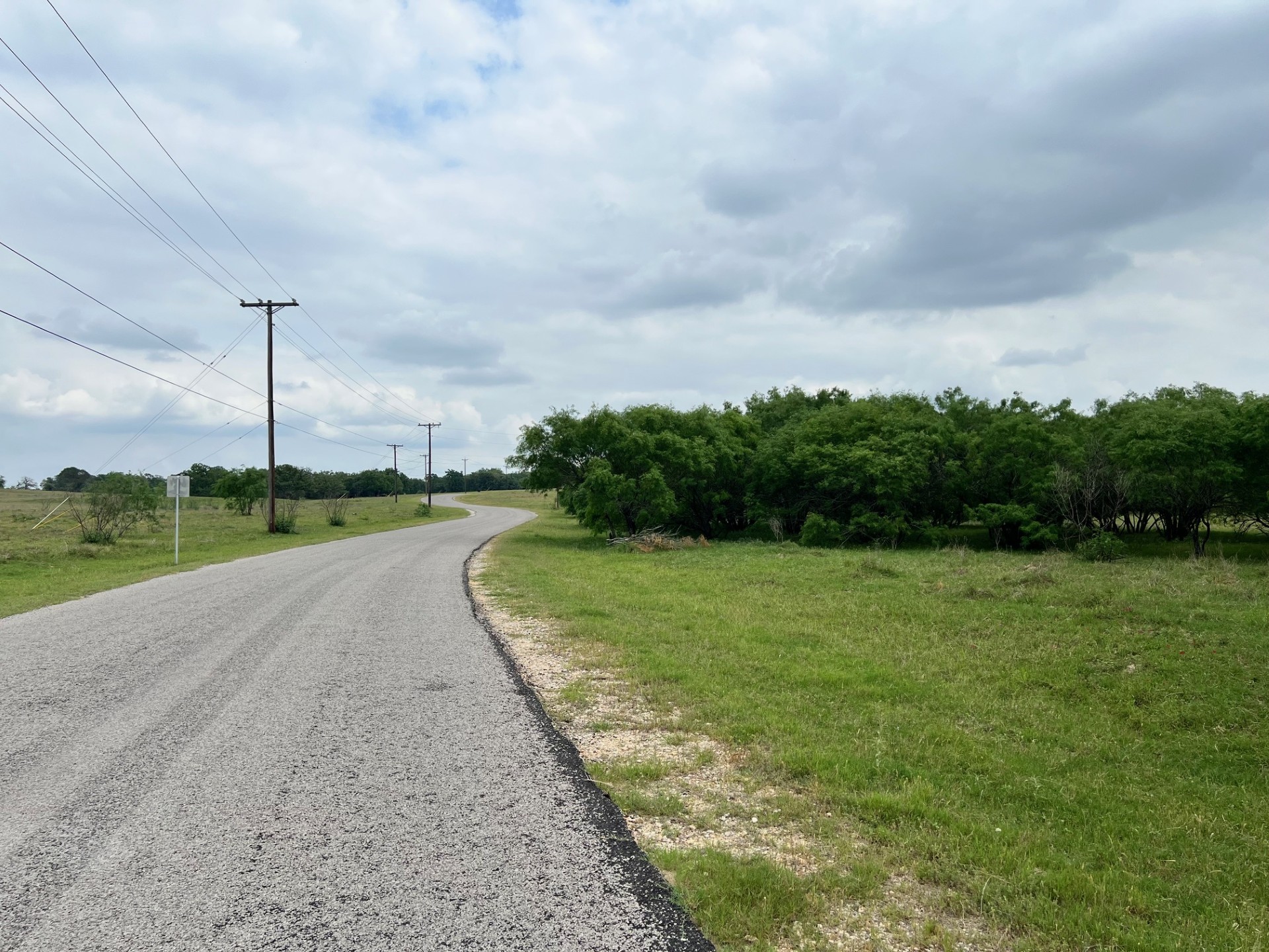Lot 17 Settlement Way Luling, TX 78648 - Photo 10 of 14 A tranquil, tree-lined road winding through a verdant landscape.