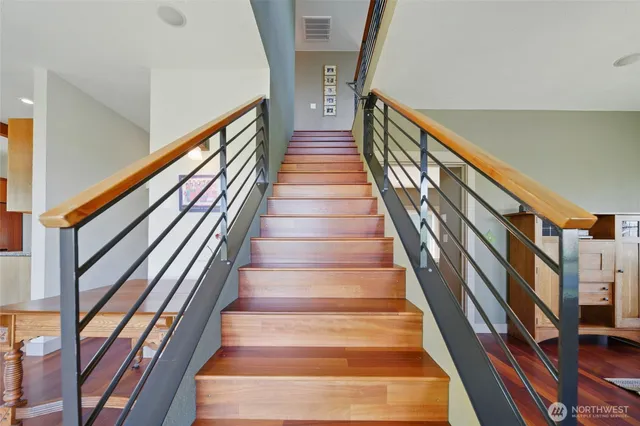 a view of staircase with lots of frames on wall and wooden floor