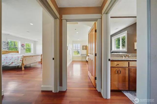 a view of a hallway with bathroom and wooden floor