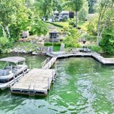 a view of a swimming pool with lawn chairs plants and large trees
