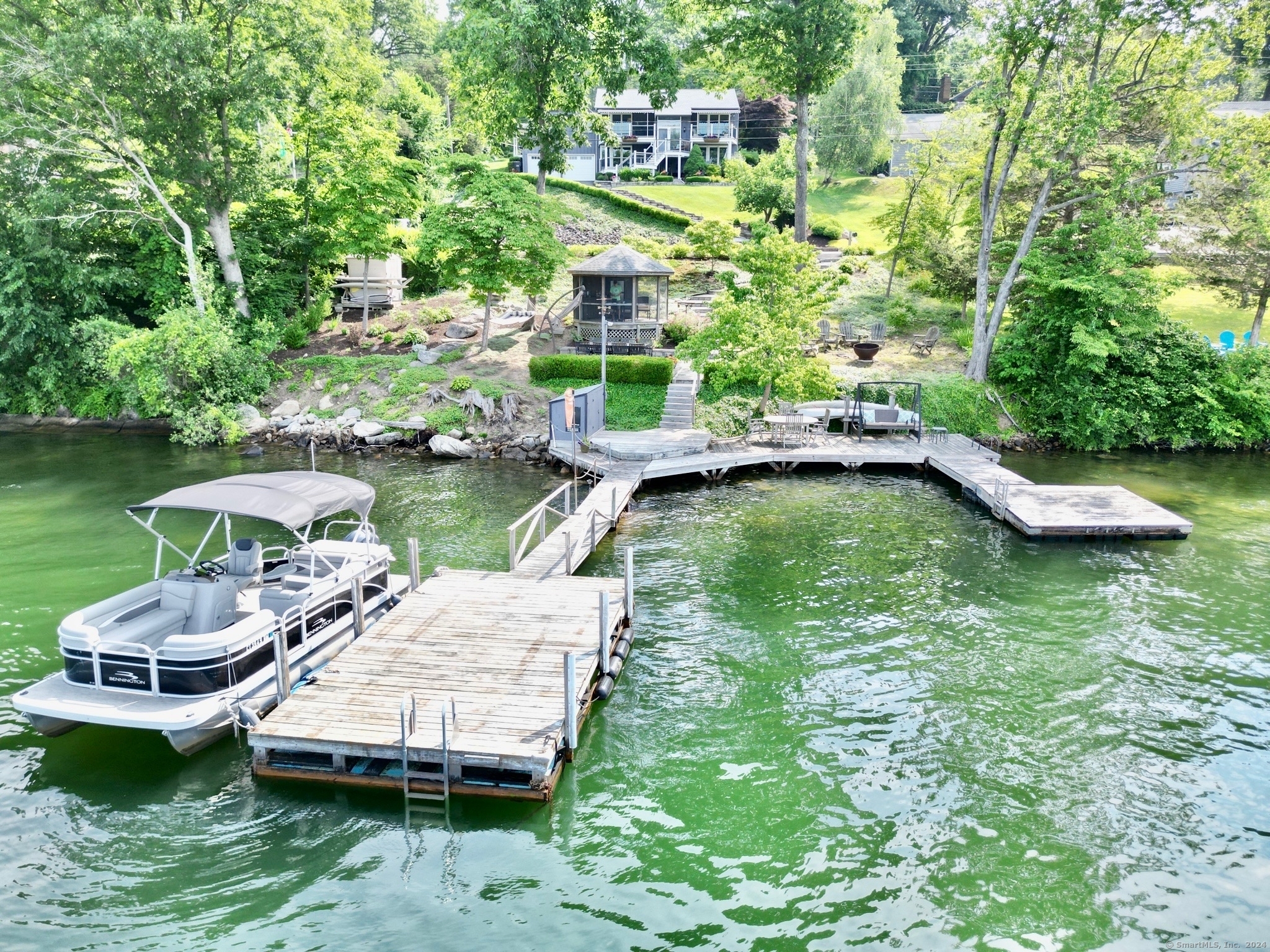 a view of a swimming pool with lawn chairs plants and large trees