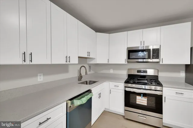a kitchen with granite countertop white cabinets and stainless steel appliances