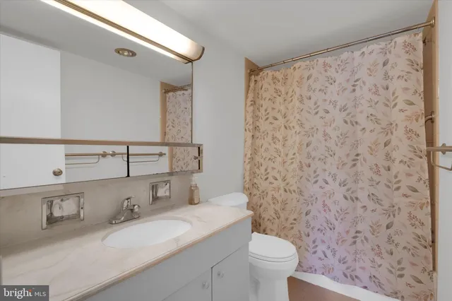a bathroom with a granite countertop sink a toilet and a mirror