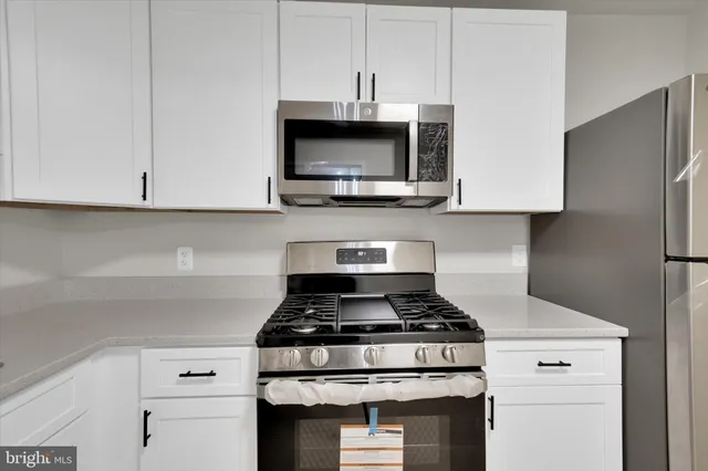 a kitchen with stainless steel appliances granite countertop a stove and a white cabinets