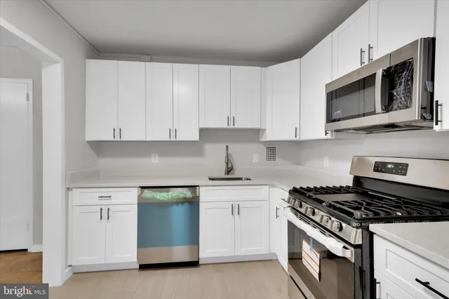 a kitchen with stainless steel appliances white cabinets and a stove top oven