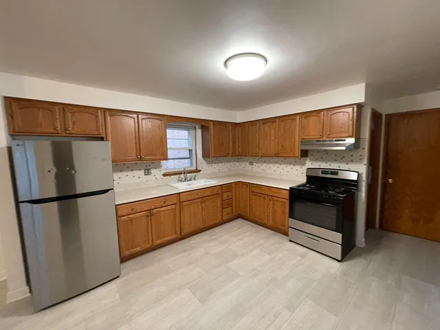 a kitchen with granite countertop a refrigerator and a stove top oven