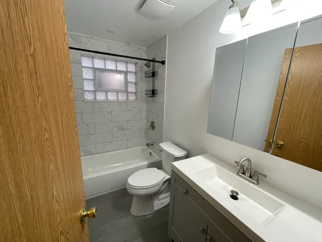 a bathroom with a bathtub shower sink mirror vanity and toilet