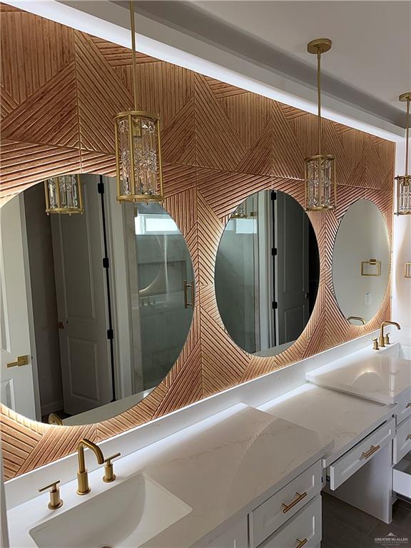 900 Azalea Street Mission, TX 78573 - Photo 5 of 12 Contemporary vanity featuring a decorative wood panel wall with three round mirrors, integrated lighting, and three crystal pendant lights
