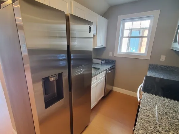 a kitchen with stainless steel appliances granite countertop a refrigerator a stove and a sink with wooden floor