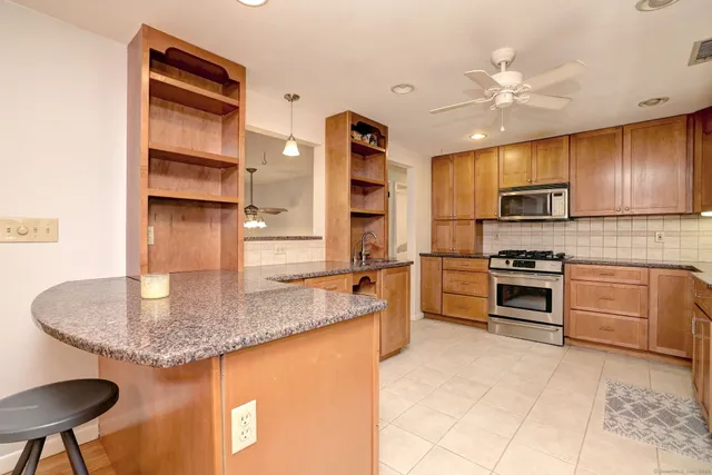 a kitchen with kitchen island granite countertop a stove a sink and a microwave