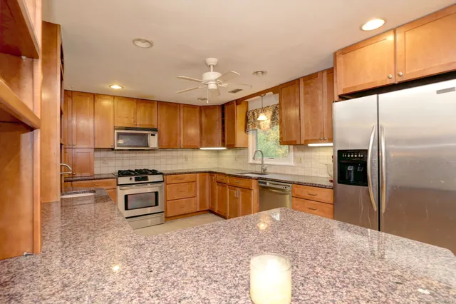a kitchen with stainless steel appliances granite countertop a refrigerator sink and stove
