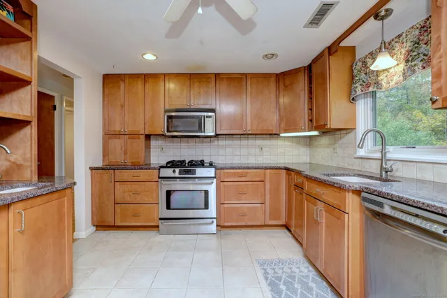 a kitchen with stainless steel appliances granite countertop a stove a sink and a microwave