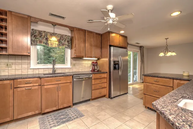 a kitchen with stainless steel appliances granite countertop a refrigerator a sink a stove and island