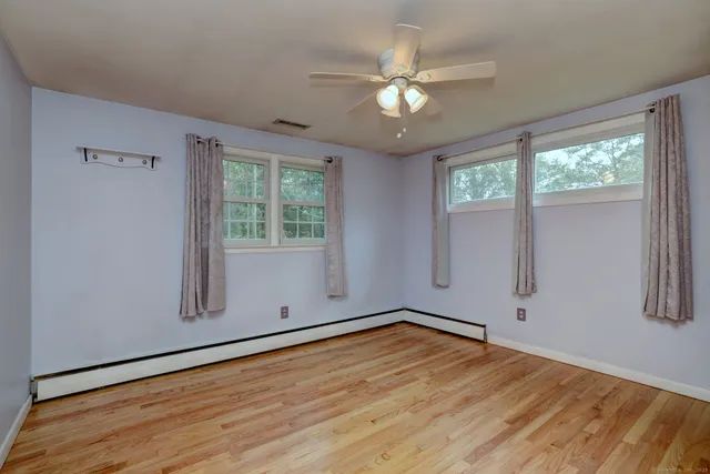 an empty room with wooden floor and windows