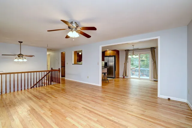 a view of empty room with wooden floor and fan
