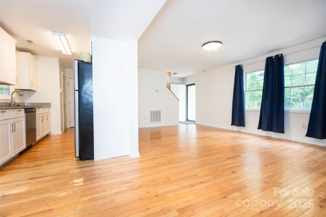 a view of an empty room with window and wooden floor