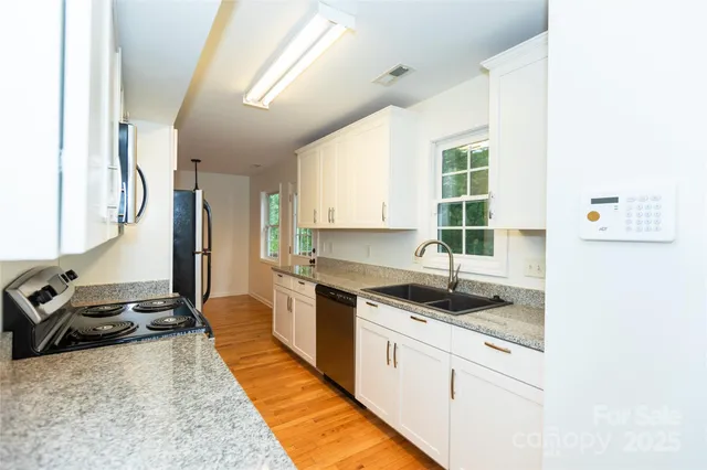a kitchen with granite countertop a sink stove and cabinets
