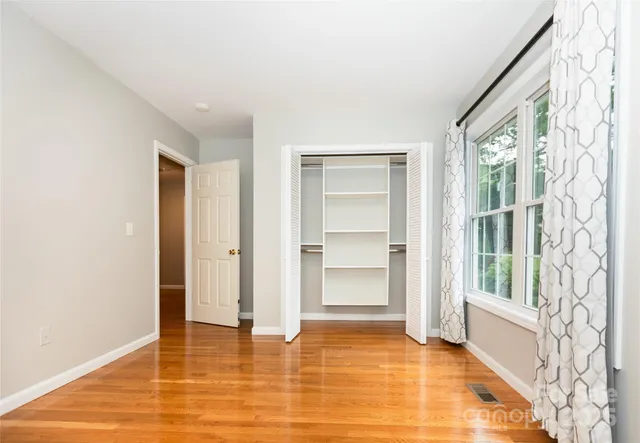 a view of an empty room with window and wooden floor