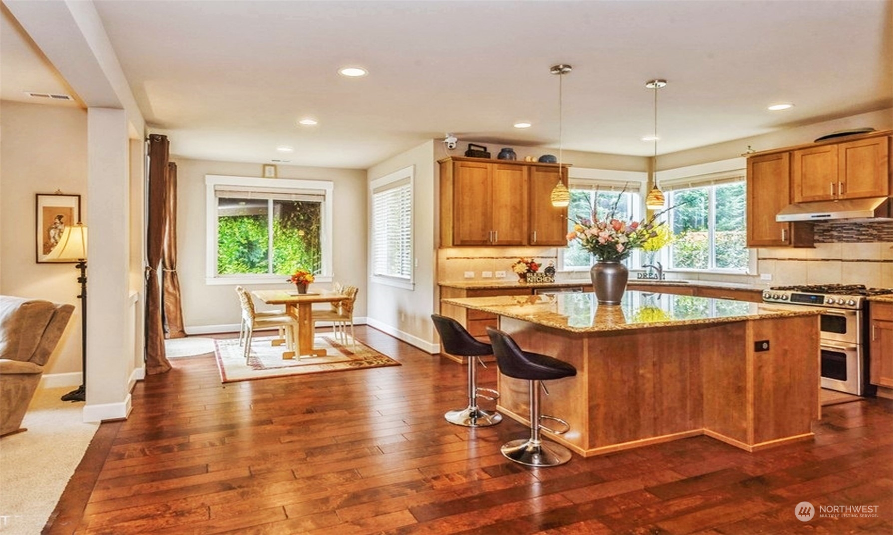 6219 Southeast 2nd Street Renton, WA 98059 - Photo 10 of 40 a kitchen with stainless steel appliances granite countertop a stove top oven a sink dishwasher a dining table and chairs with wooden floor