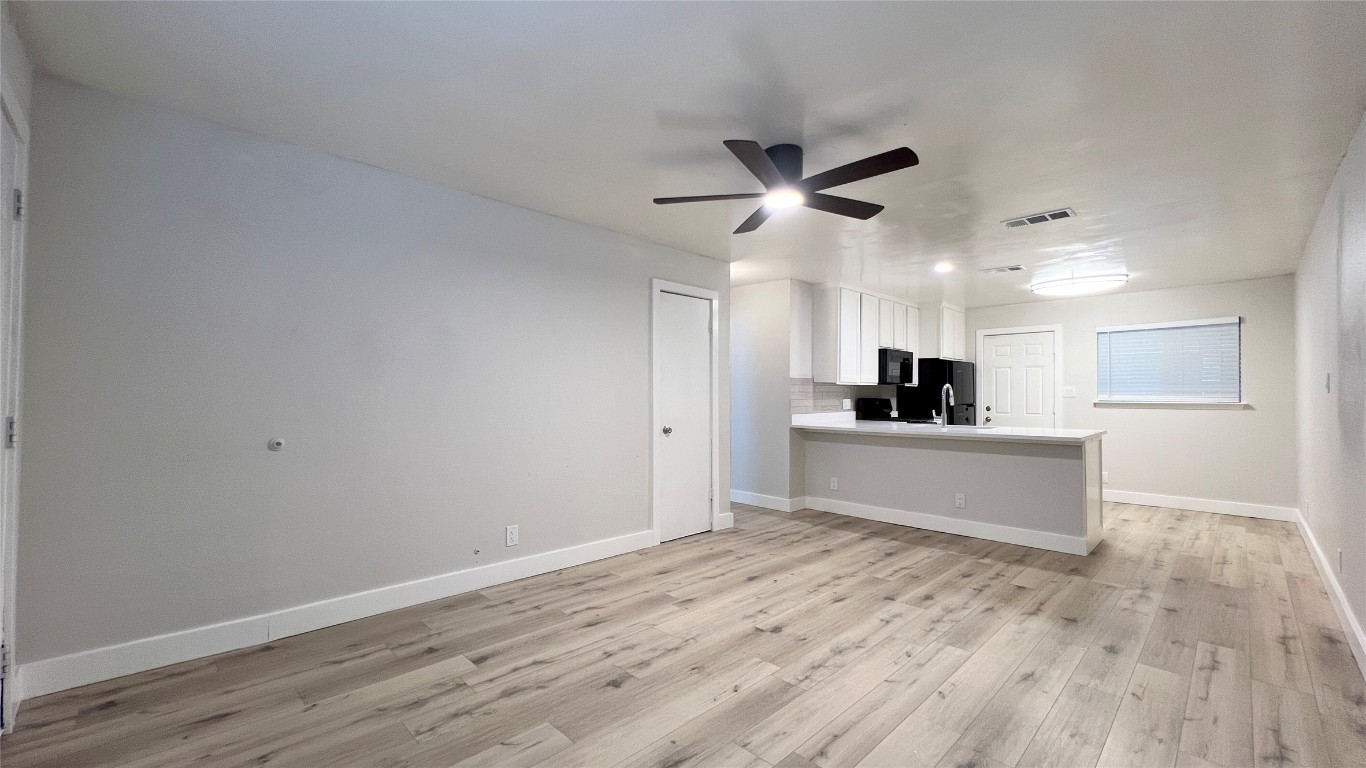 11103 Renel Drive, Unit A Austin, TX 78758 - Photo 3 of 7 a view of a kitchen with wooden floor and a ceiling fan
