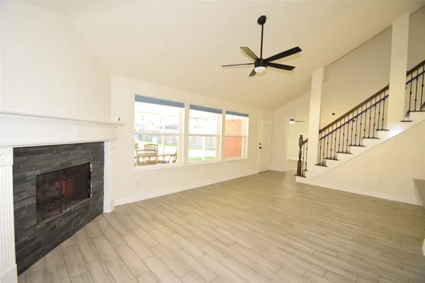a view of an empty room with wooden floor fireplace and a window