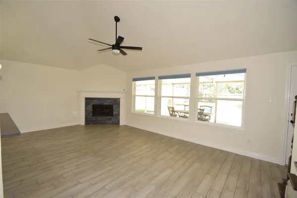 an empty room with windows and ceiling fan