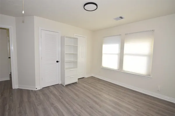 an empty room with wooden floor and windows