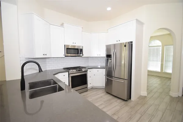 a kitchen with stainless steel appliances granite countertop a refrigerator a stove a sink and a microwave