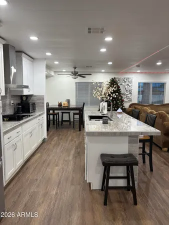 a kitchen with stainless steel appliances kitchen island granite countertop a dining table chairs sink and cabinets