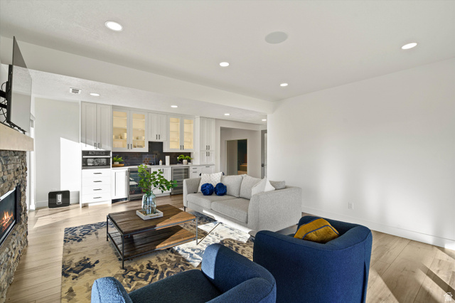 4499 North Seven Bridges Road, Unit 9 Eden, UT 84310 - Photo 33 of 65 Integrated living space featuring a stone-clad fireplace, light wood-finish flooring, recessed lighting, white built-in cabinetry with glass-front uppers, and stainless steel beverage refrigerators