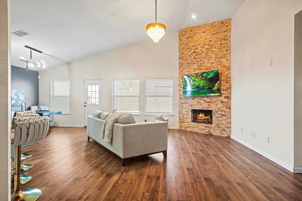 1412 Cheyenne Road Wylie, TX 75098 - Photo 3 of 24 Living room featuring a chandelier, high vaulted ceiling, dark wood-style floors, and a stone fireplace