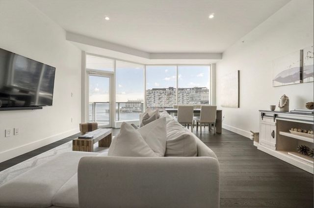 a living room with furniture a flat screen tv and a floor to ceiling window