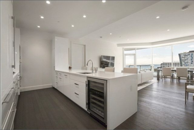 a large white kitchen with lots of counter space wooden floor and stainless steel appliances