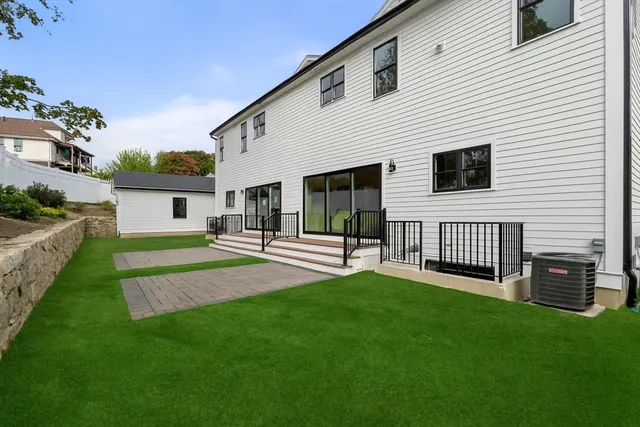 a view of a house with a yard and a large tree