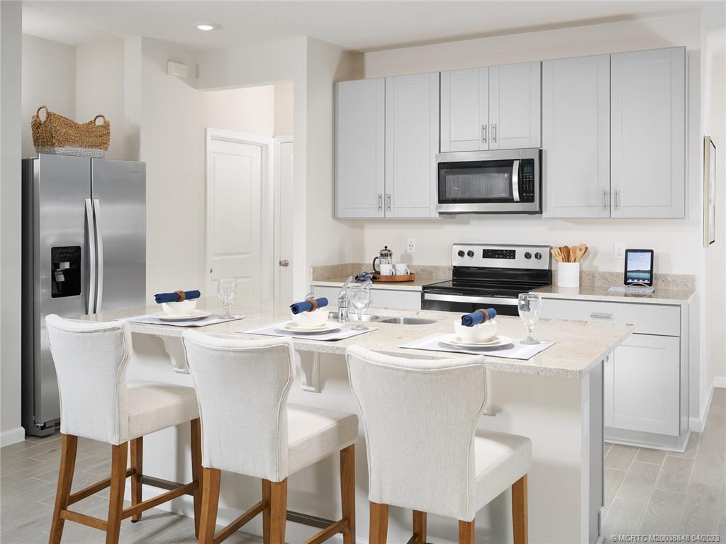 5630 Southeast Edgewater Circle Stuart, FL 34997 - Photo 3 of 9 a kitchen with stainless steel appliances granite countertop a sink a stove a microwave a refrigerator and white cabinets