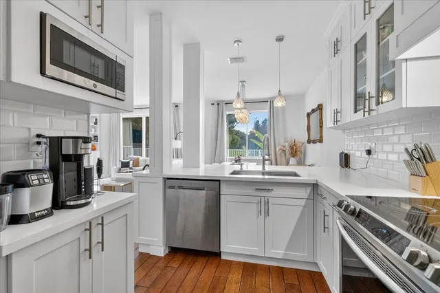 a kitchen with stainless steel appliances a sink cabinets and wooden floor